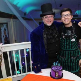 a group of people sitting at a table with a birthday cake
