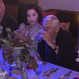 a group of people sitting at a table with a birthday cake