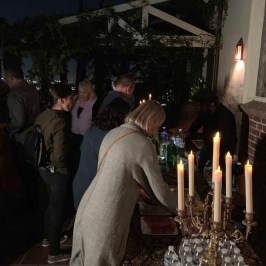 a person standing in front of a birthday cake with lit candles