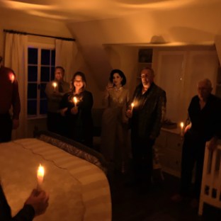 a group of people standing in front of a cake with lit candles